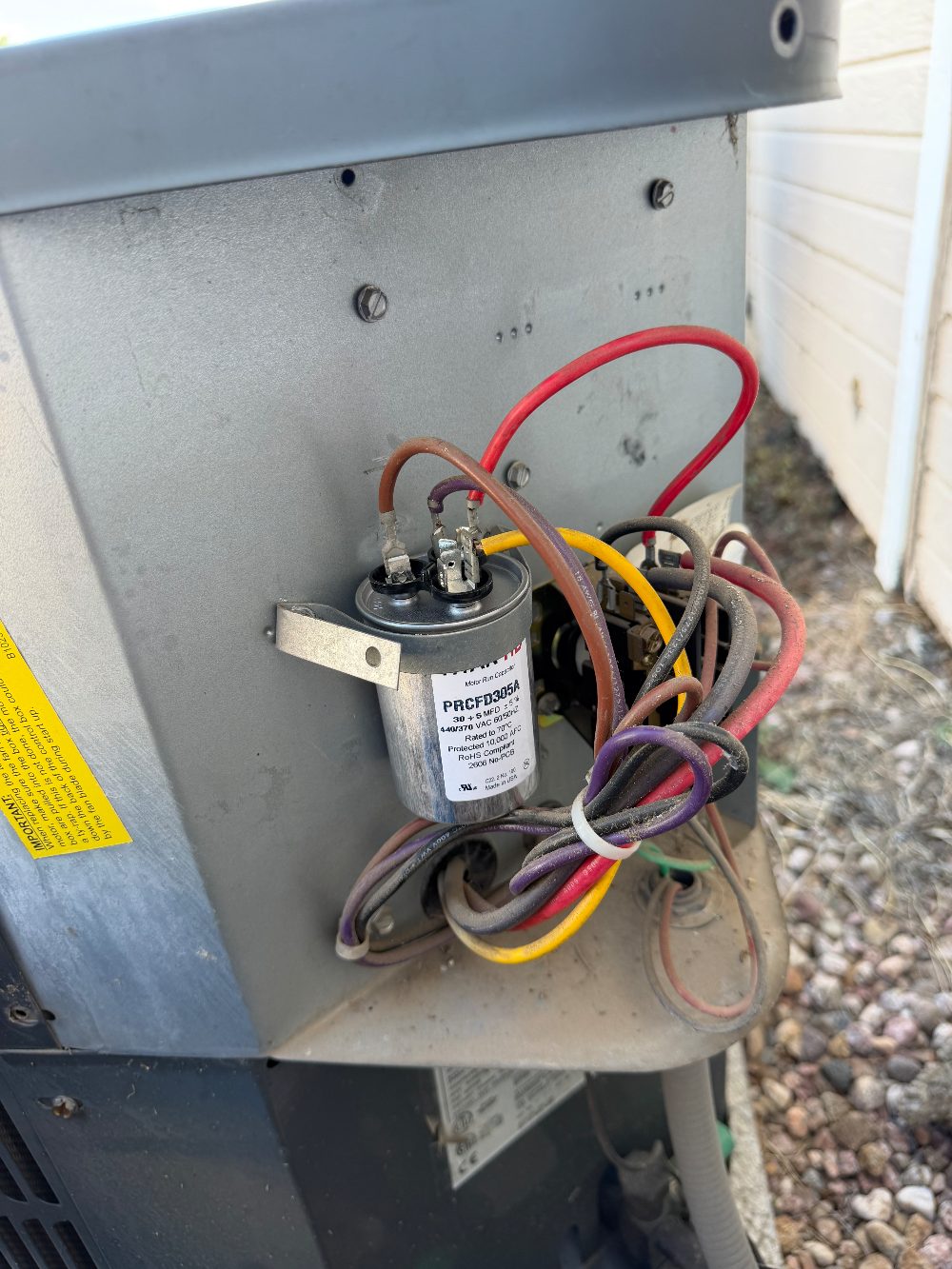 A new 30+5 microfarad dual run capacitor installed in an outdoor AC condenser unit